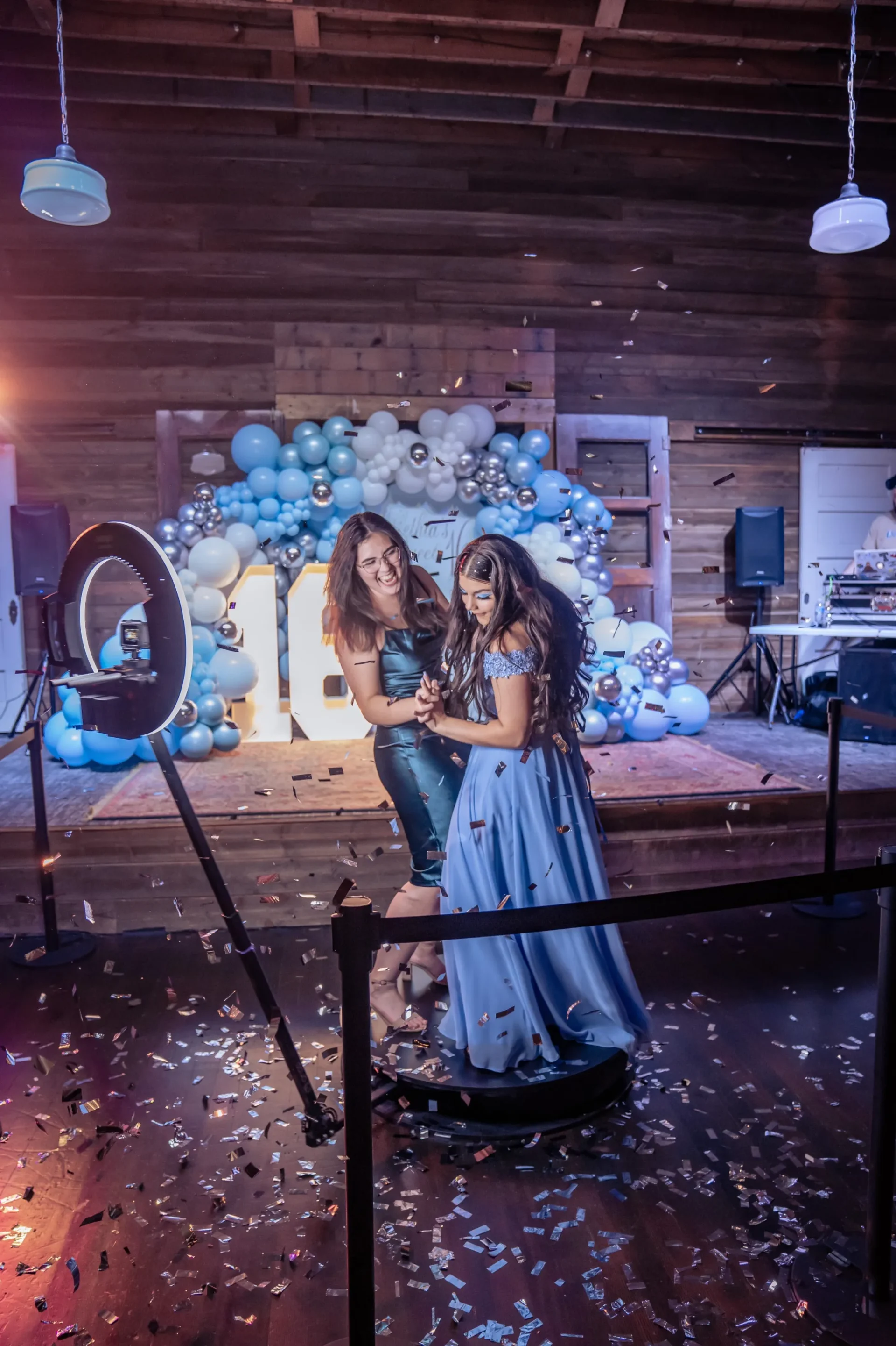 Two people smiling and dancing in a decorated venue with balloons and confetti.