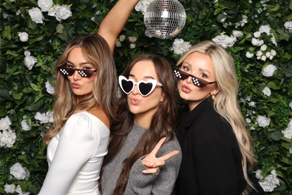 Three women posing in front of a flower backdrop