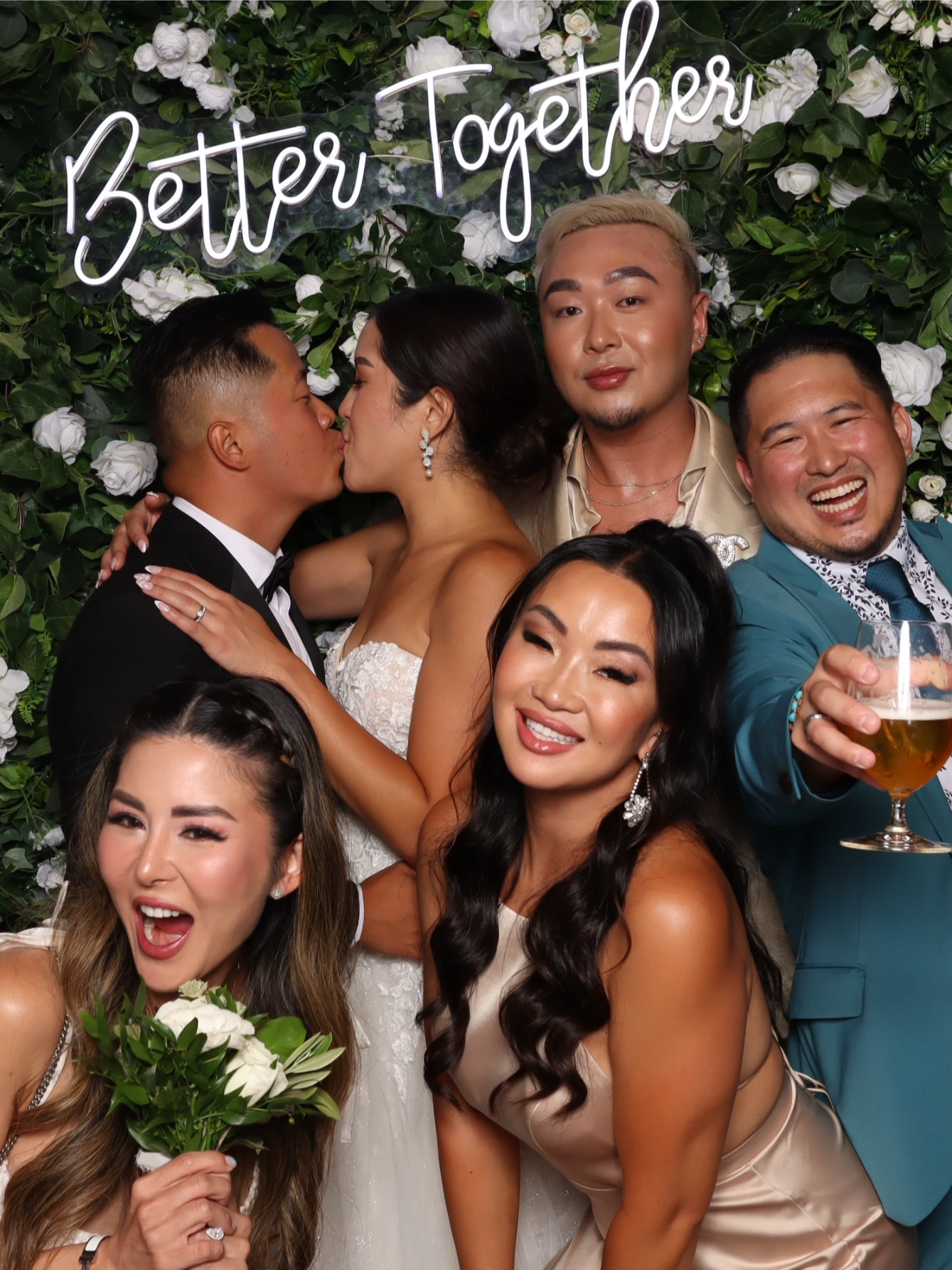 A wedding celebration with six people. Background of greenery and white roses.