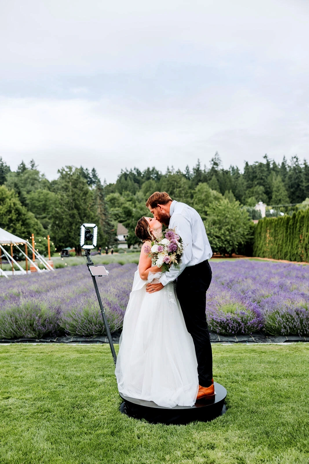 A bride and groom kissing on a small platform in front of the professional photo booth camera